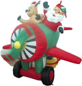 Santa in pilot goggles flying a red and green propeller plane with a reindeer passenger