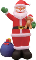 Giant Santa inflatable waving and holding a teddy bear with a blue gift sack at his feet