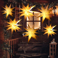 Several glowing warm white Moravian star lanterns hanging outside a window at night
