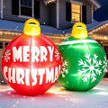 Giant red Merry Christmas and green snowflake ornament ball inflatables on a lawn at night