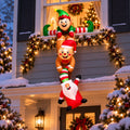 Hanging chain inflatable of an elf holding a reindeer and an upside-down Santa on the front of a house