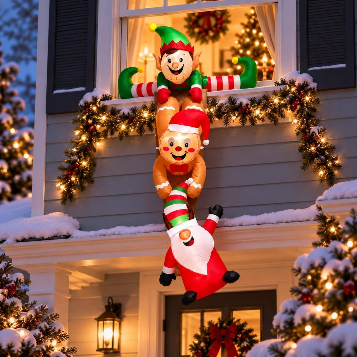 Hanging chain inflatable of an elf holding a reindeer and an upside-down Santa on the front of a house