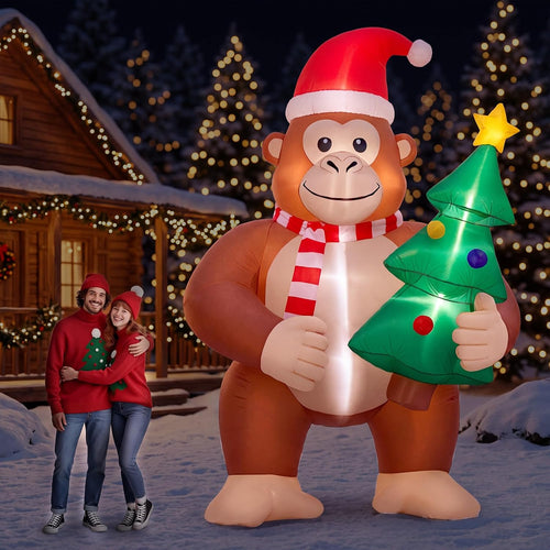 Brown Bigfoot inflatable in a Santa hat and scarf holding a small tree beside a couple