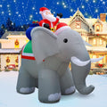 Santa riding a large gray elephant inflatable in front of a lit house