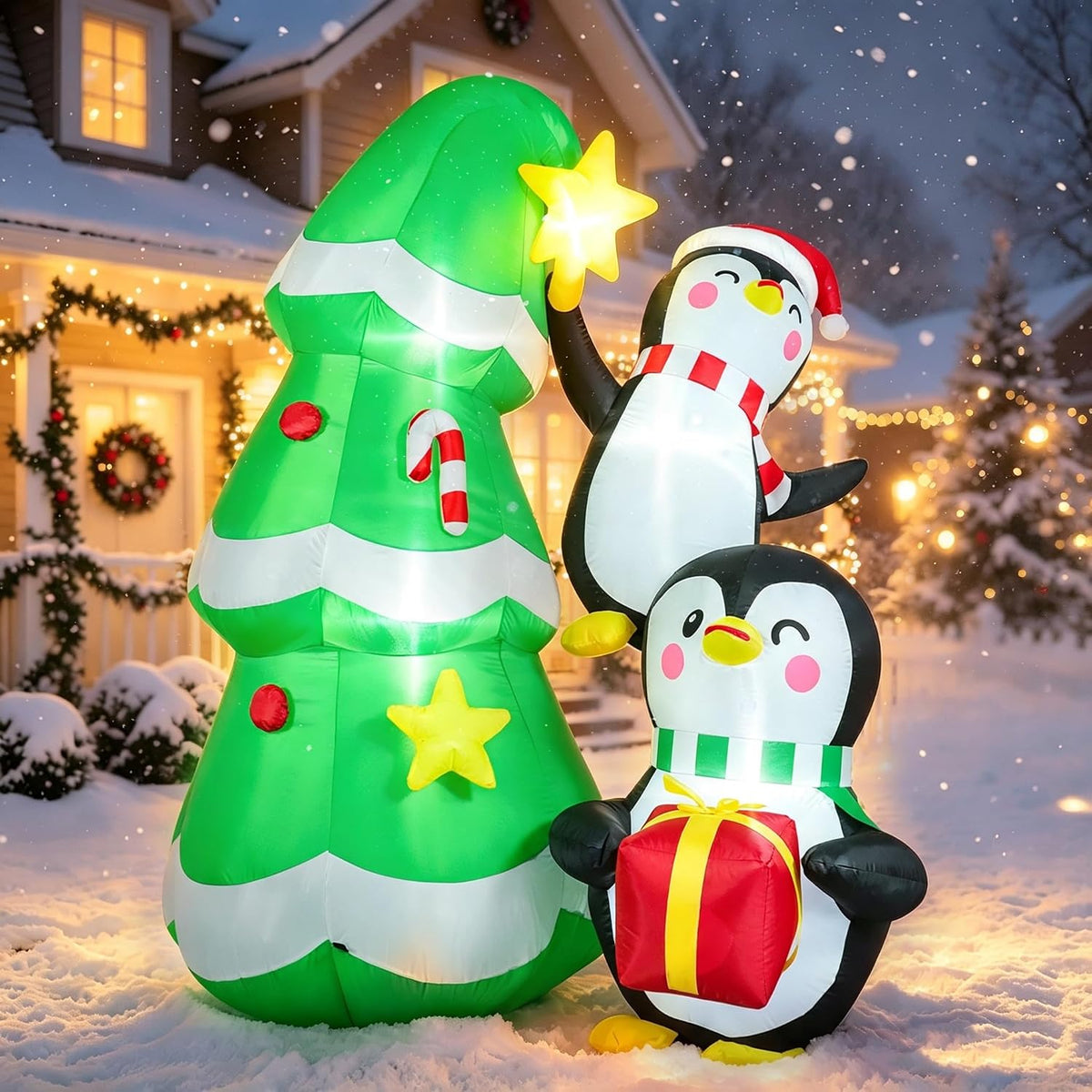 Green Christmas tree inflatable with a star and two penguins in Santa hats in a snowy yard
