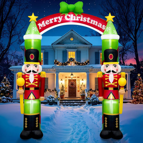 Two nutcracker soldier inflatables holding a Merry Christmas arch over a snowy front walk