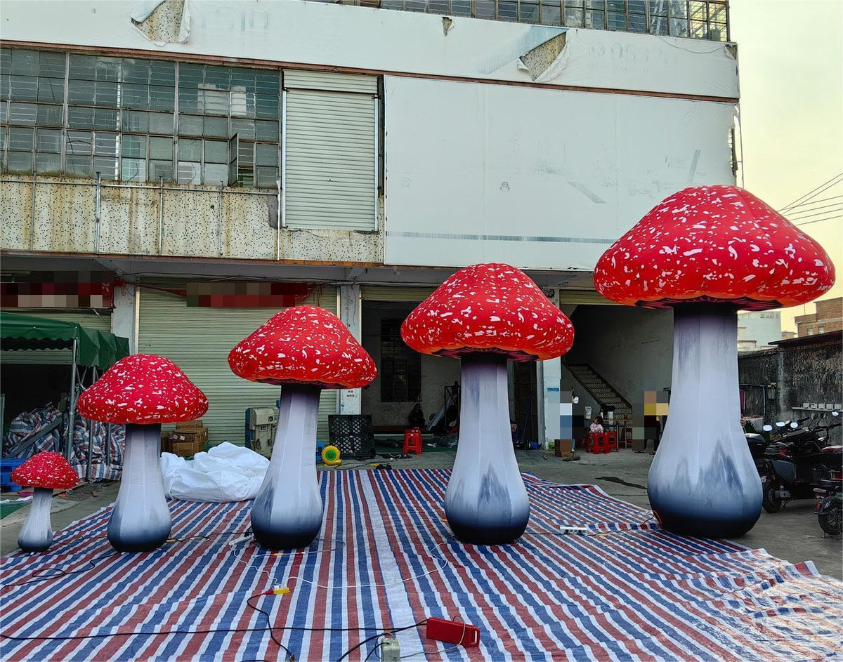Several red and white spotted mushroom inflatables in different sizes set up at an outdoor event
