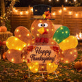 Lighted sparkly turkey in a top hat holding a Happy Thanksgiving sign on a patio