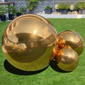 Large shiny gold inflatable mirror balls on a green lawn