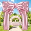 Metallic rose gold bow inflatable arch over a garden path leading to a party