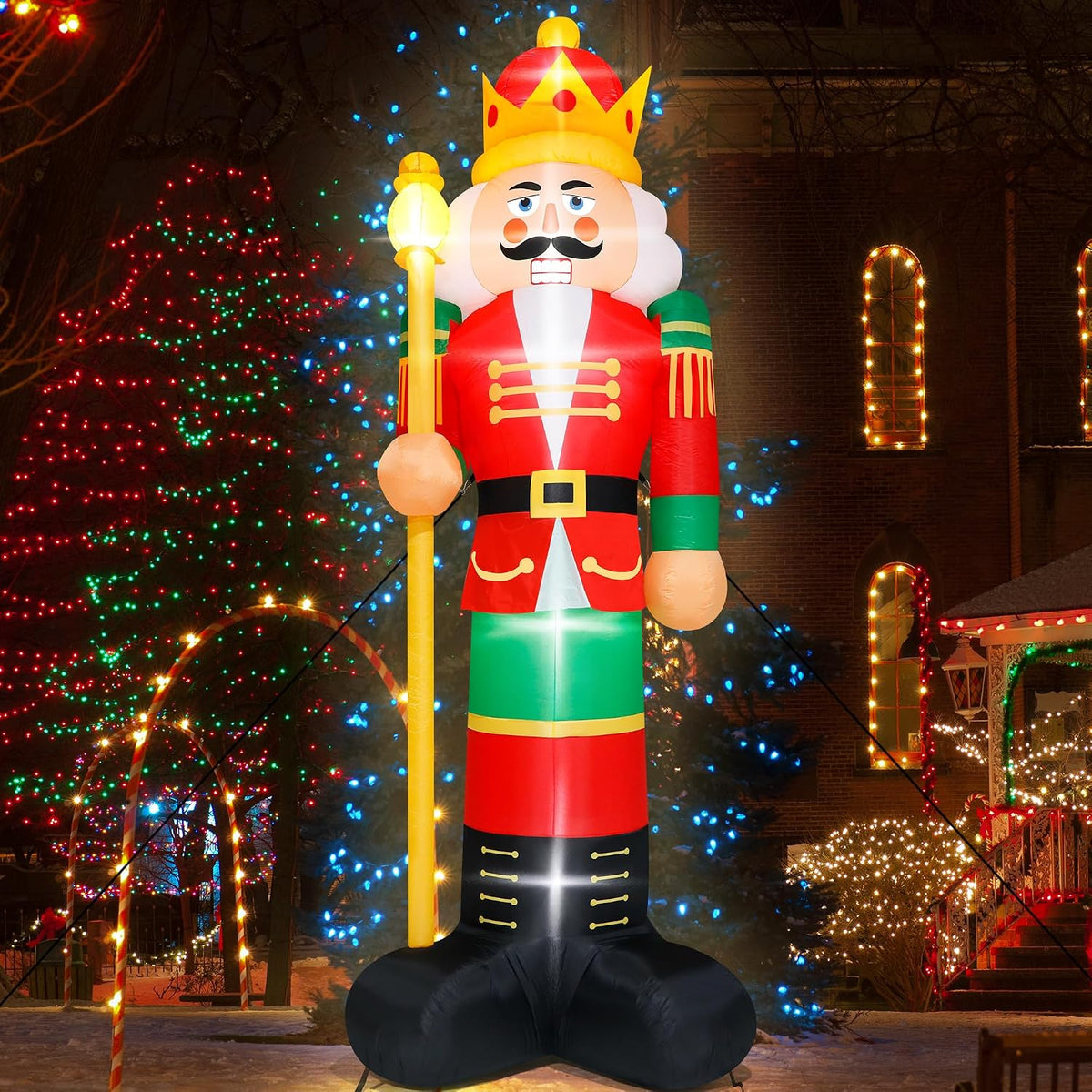 Giant nutcracker inflatable in a red coat and gold crown holding a scepter at night