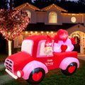 Gnome driving a red Valentine pickup truck inflatable with heart wheels and hearts in the bed at night