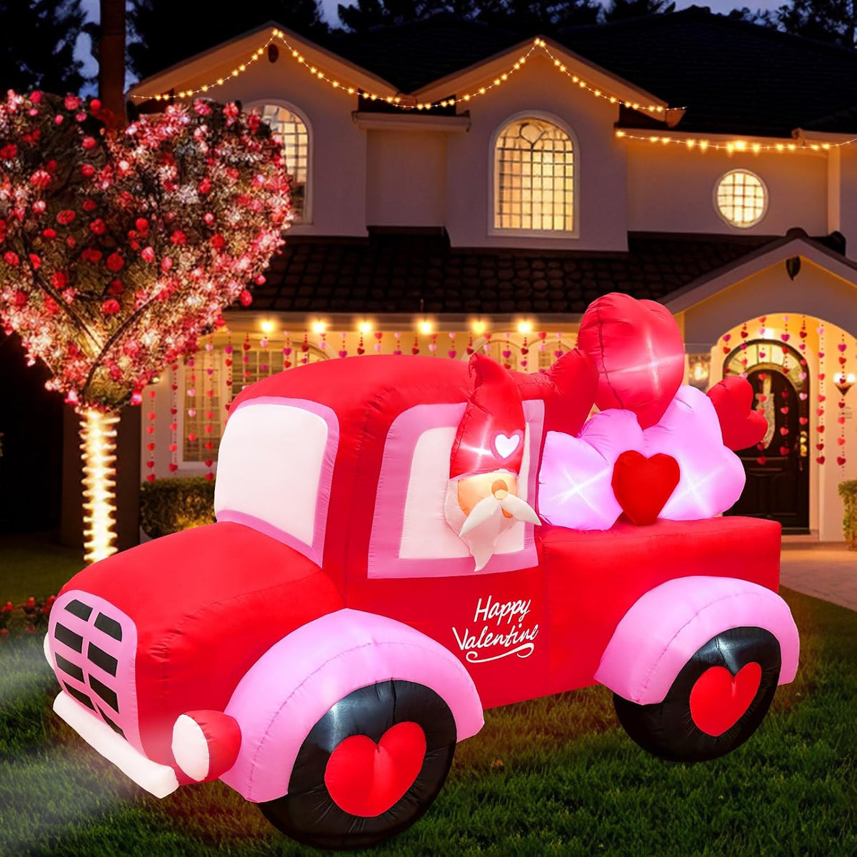 Gnome driving a red Valentine pickup truck inflatable with heart wheels and hearts in the bed at night
