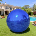 Shiny blue inflatable mirror ball on a lawn beside a pool