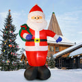 Giant Santa inflatable with open arms and a green gift sack in a snowy yard