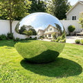 Shiny silver inflatable mirror ball on a green lawn reflecting a house